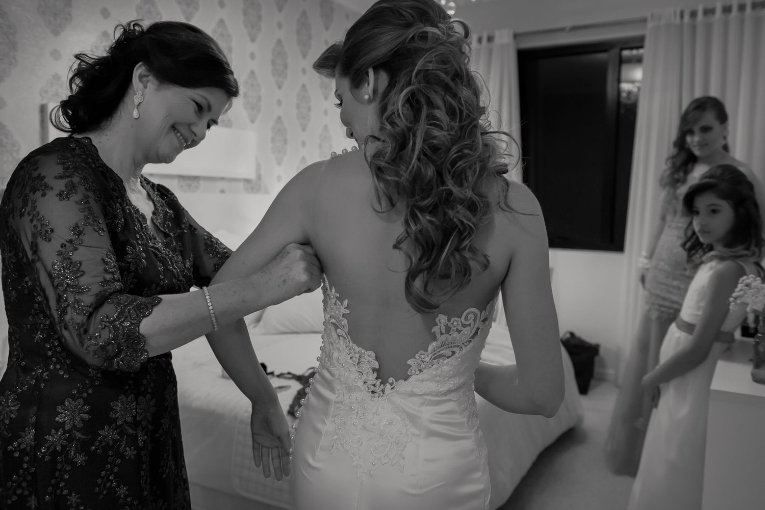 A close-up view of a white wedding dress being adjusted in a bridal preparation room.