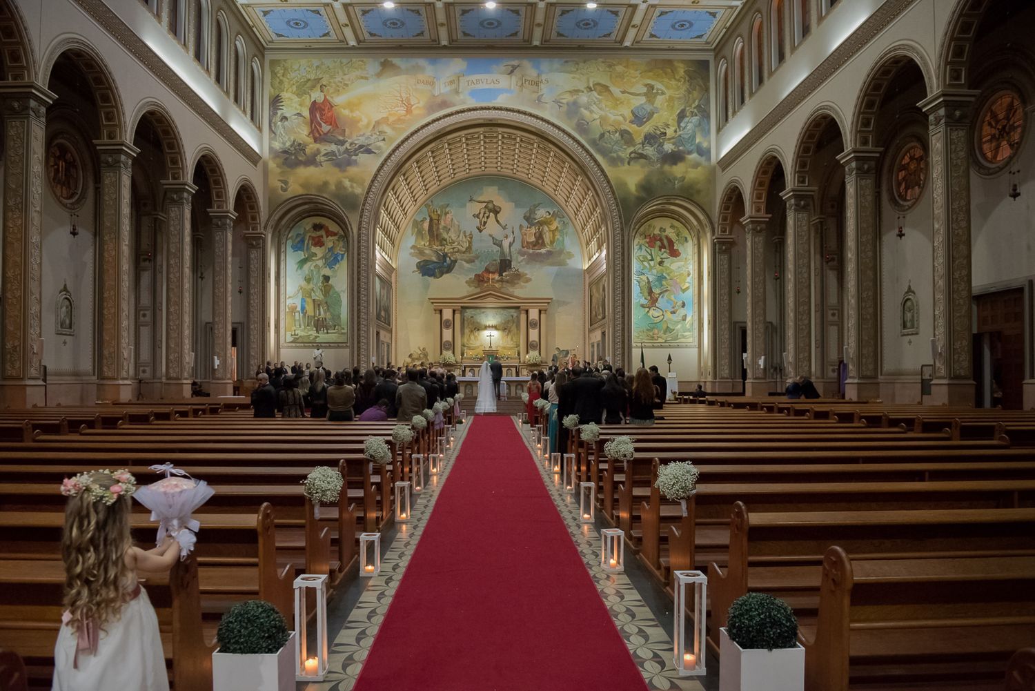 Stunning cathedral interior with painted ceilings, arched columns and red carpet down center aisle.