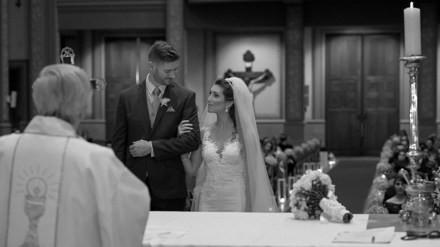 Black and white photo of a wedding ceremony at the altar in a traditional church setting.