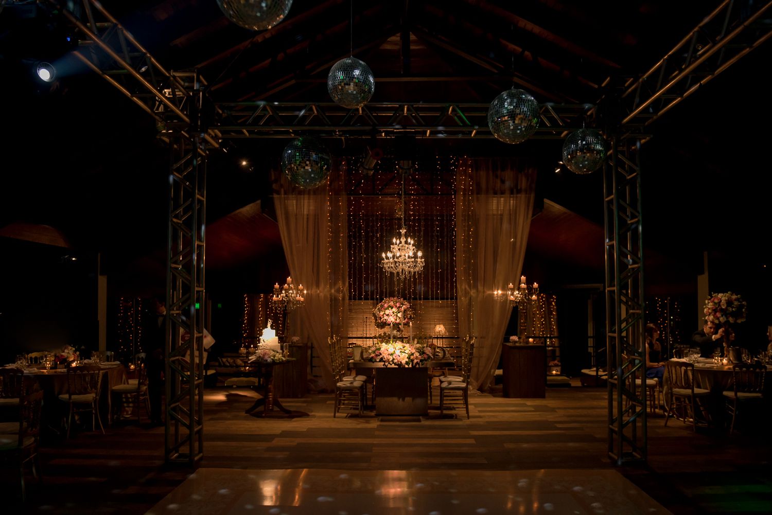 Elegant wedding reception venue with chandeliers and stage lighting creating dramatic ambiance.