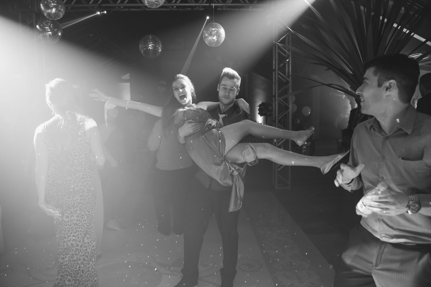 A black and white photo capturing energetic dancing at a wedding reception.