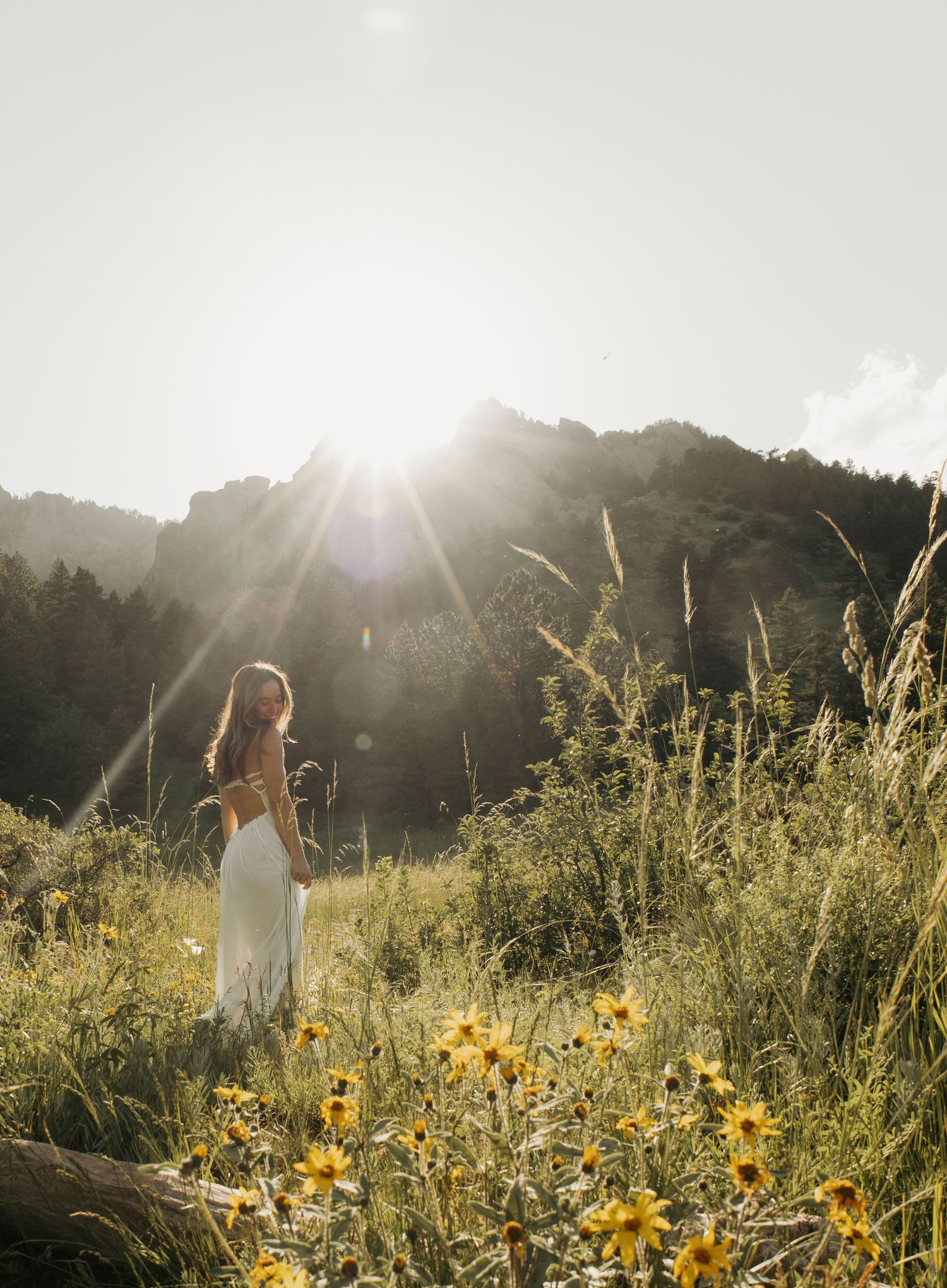 A couple in wedding attire dance together by a river in a dreamy forest setting surrounded by spring foliage.