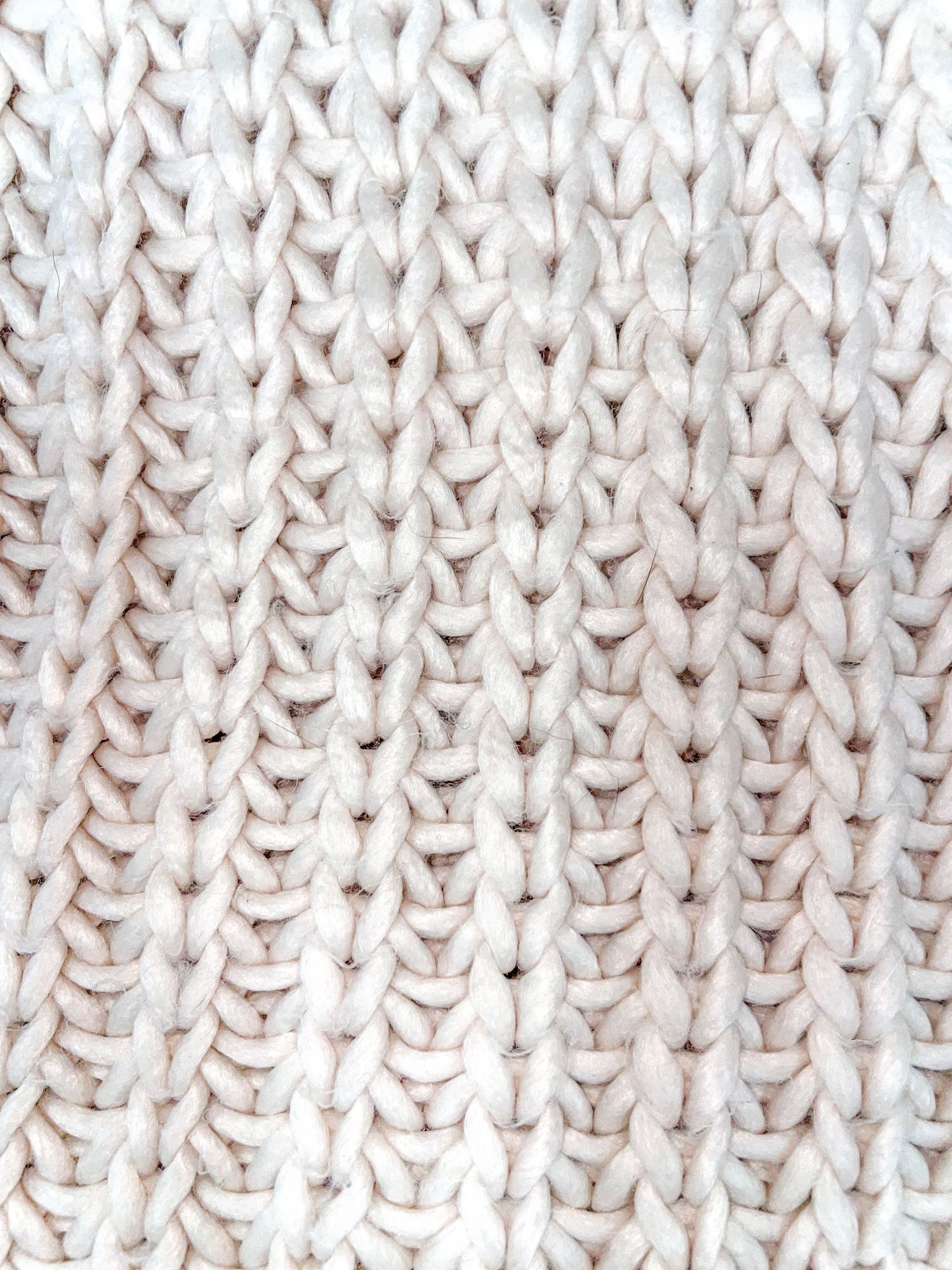 Close-up of white knitted fabric showing detailed stitch pattern and texture.
