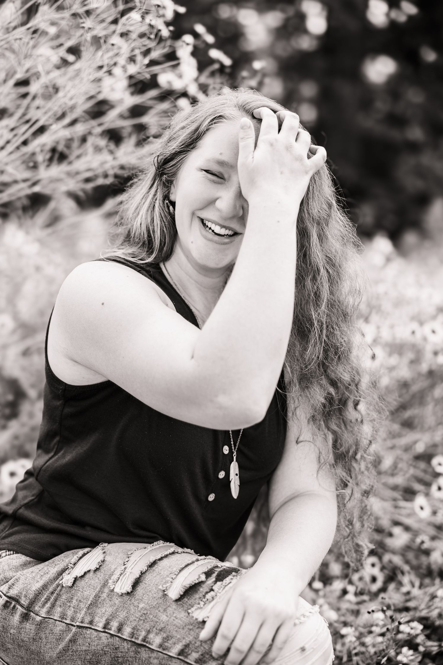 Black and white candid photo of a girl laughing at the camera.