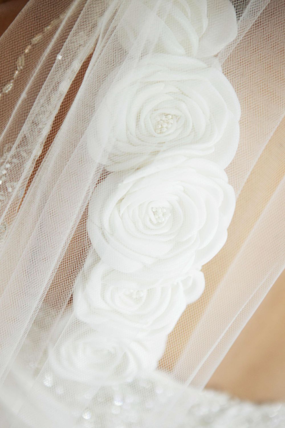 Delicate white fabric roses adorning a wedding veil with soft tulle details.