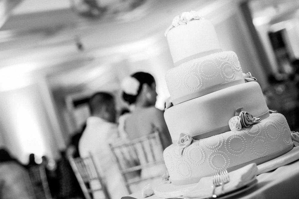 A classic white wedding cake with delicate swirl designs on display at an elegant reception venue.