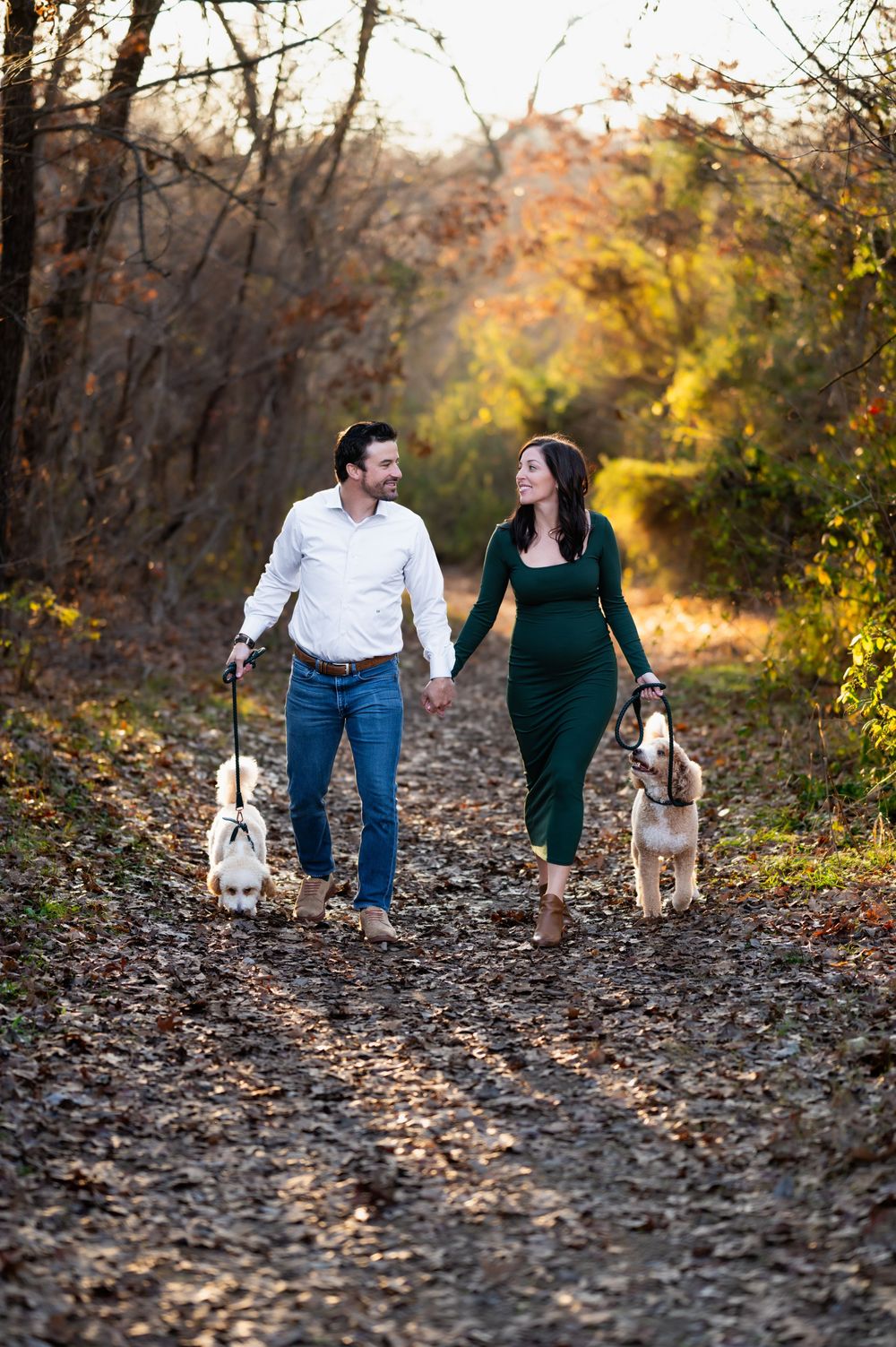 mesquite family photographer captures couple during maternity photo session, each holding leash of goldendoodle while holding hands