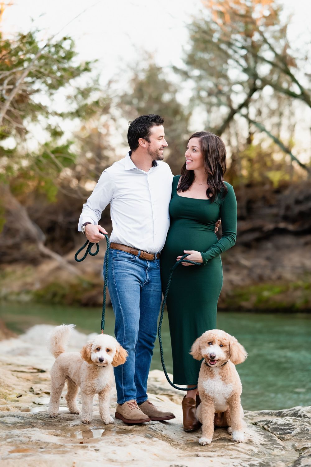 dallas area maternity photo session; mom holds bump dad holds the leash of golden doodles in richardson while looking at each other lovingly