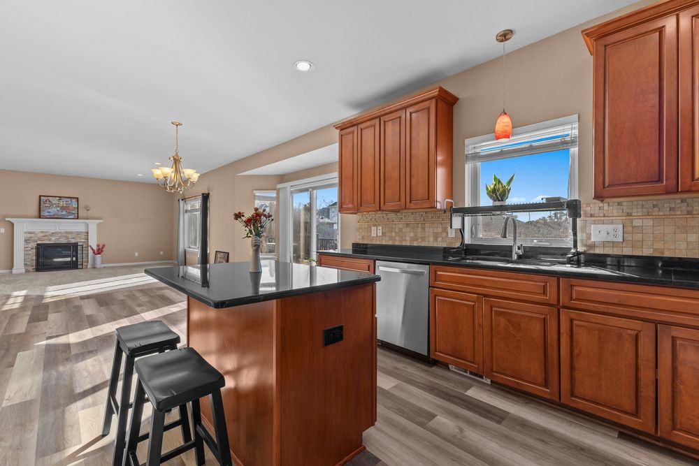 Open kitchen with cherry wood cabinetry, granite counters, center island, and view into living room.