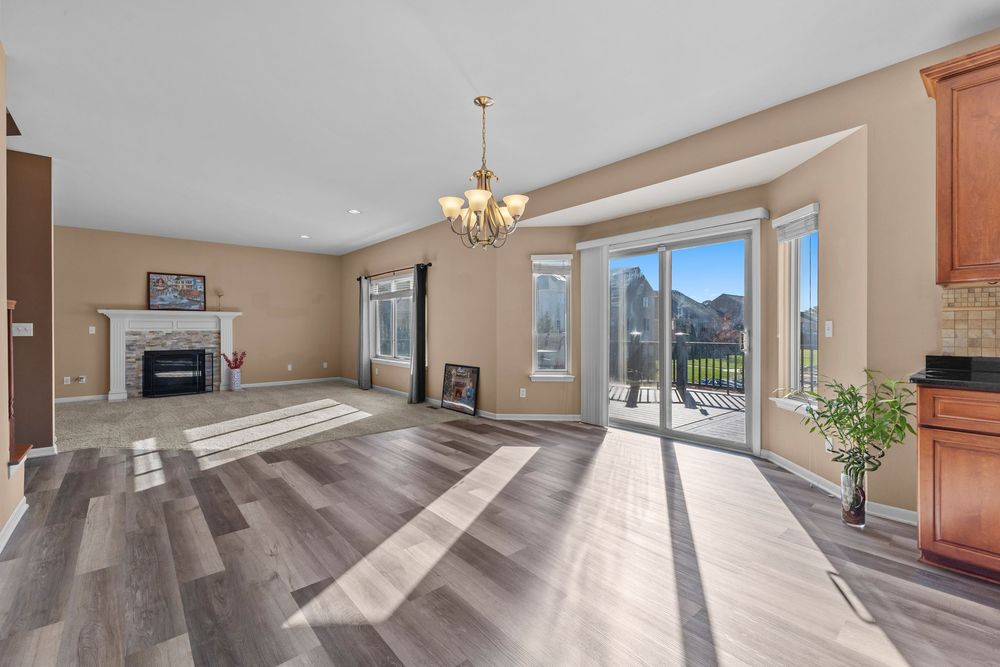Open living area with hardwood floors, fireplace, chandelier, and sliding glass doors leading to a patio.