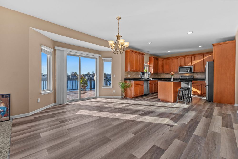 Open kitchen and dining area with hardwood floors, island, stainless appliances, and sliding glass doors.