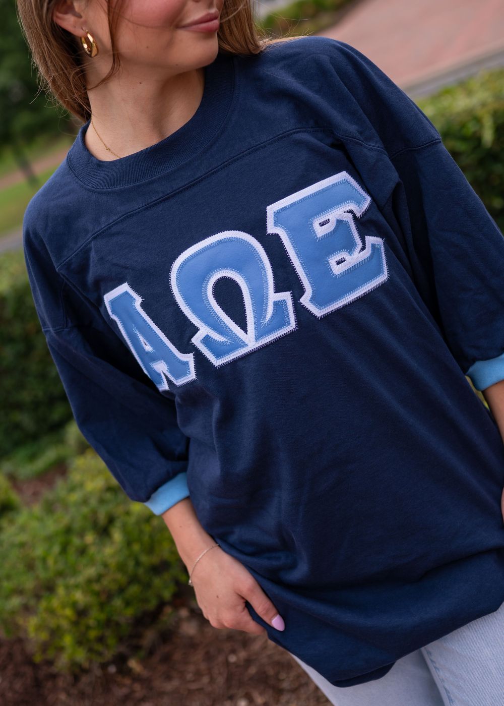 Navy blue t-shirt with light blue Greek letters AQE displayed across the chest.