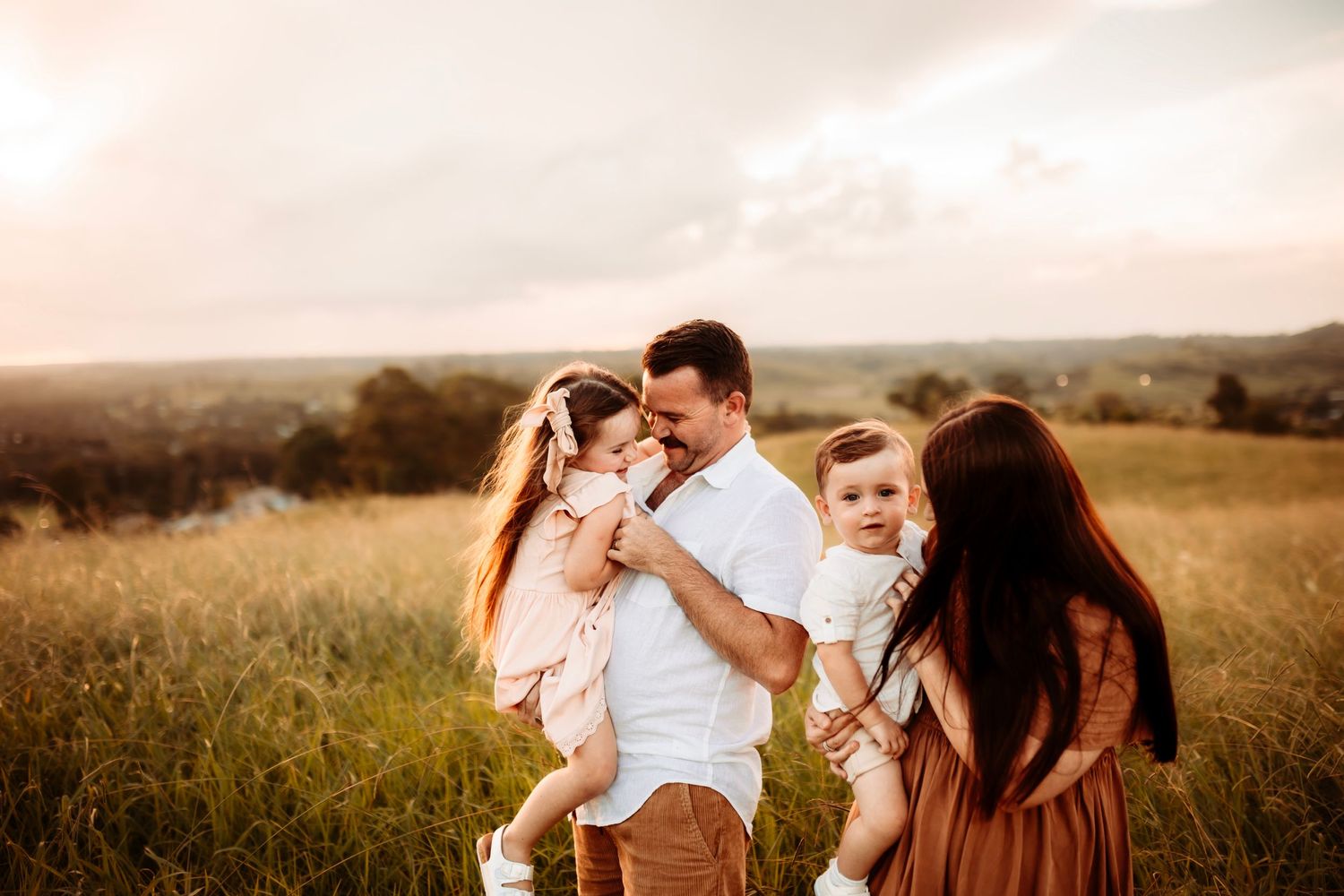 A happy family sharing a joyful moment in a sunlit meadow.