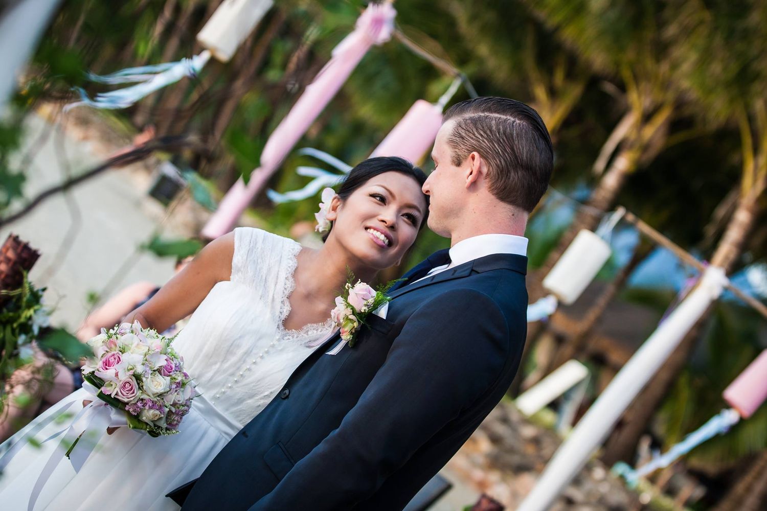 A tender wedding moment captured between a couple beneath decorative streamers.