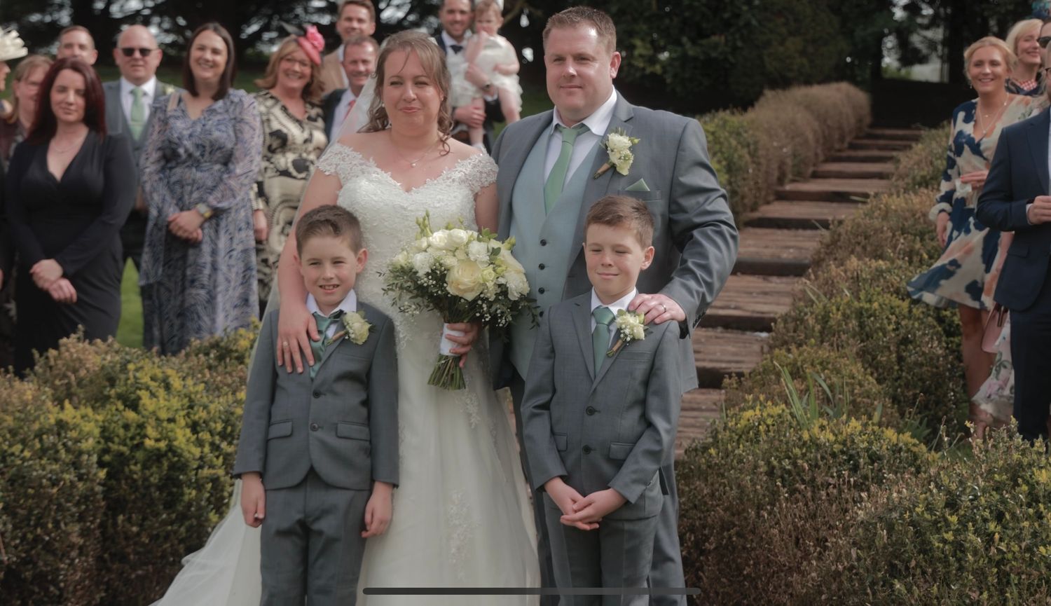 Wedding group portrait on garden steps with formal attire.