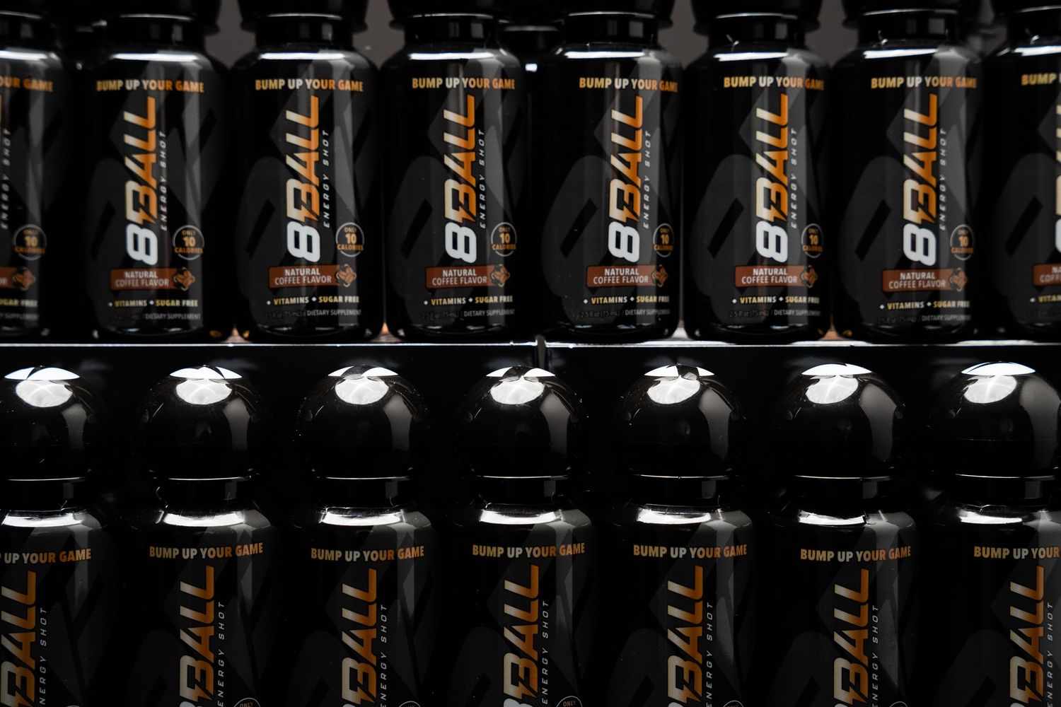 Rows of black G FUEL energy drink cans lined up on dark shelves with identical branding and packaging.