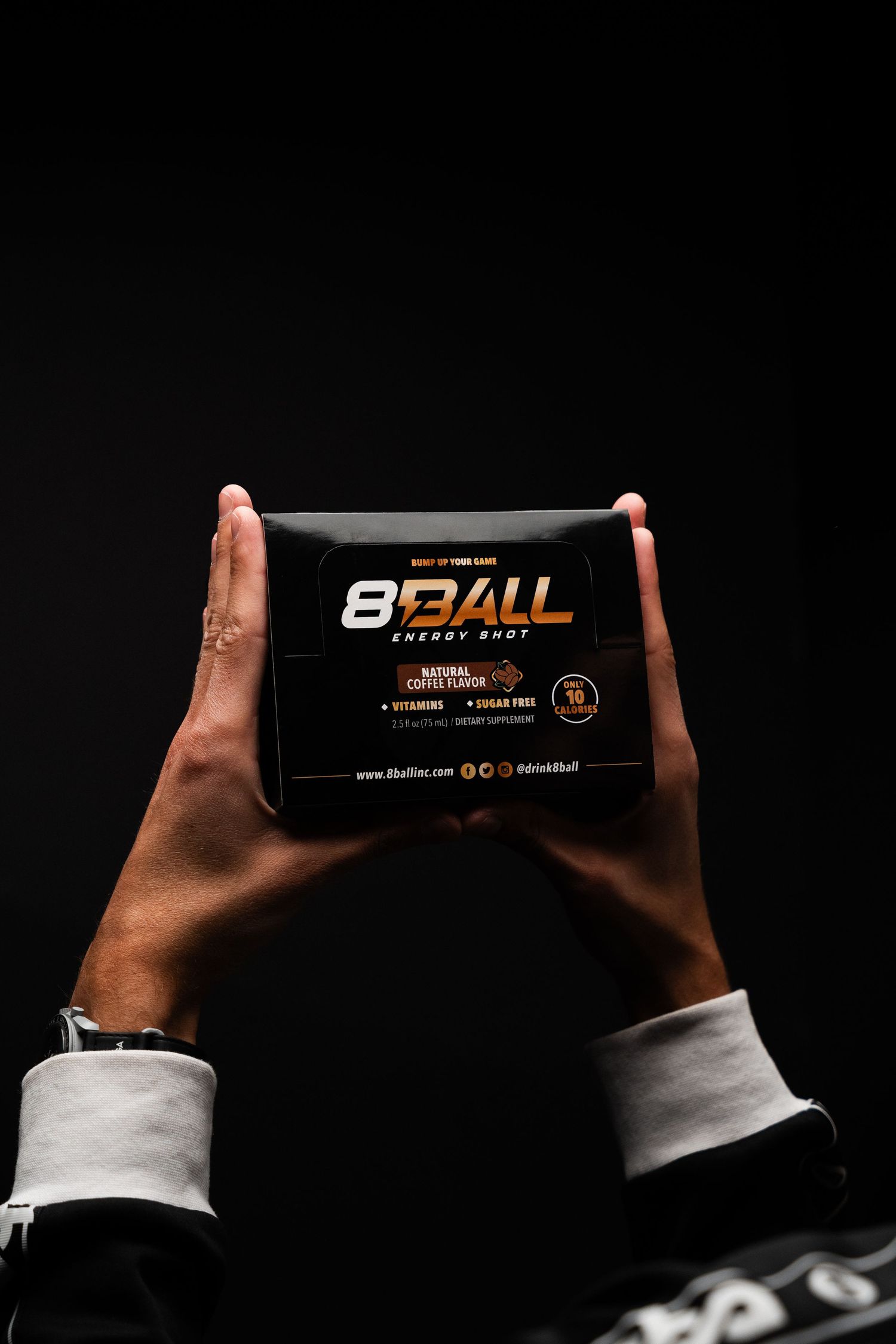 Hands holding 8Ball energy soap bar against dark background showing product branding and packaging.