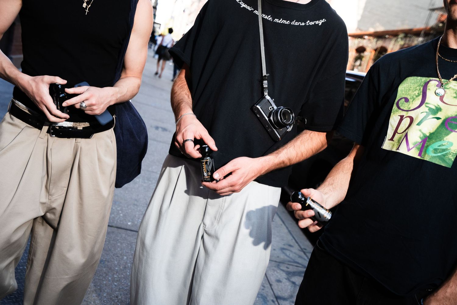 People in casual attire holding phones and mobile devices while wearing black and gray clothing.
