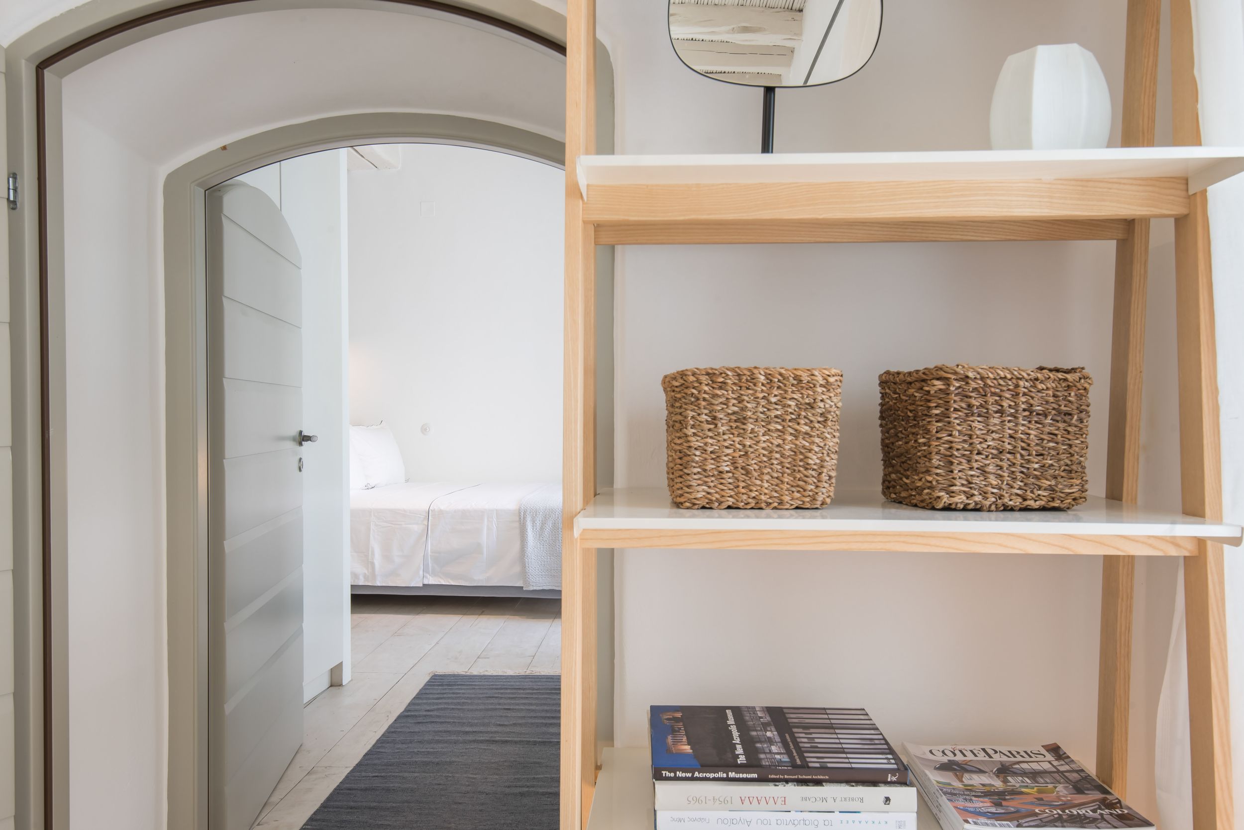 Light and airy interior view showing doorway and wooden shelving unit with woven baskets and books.