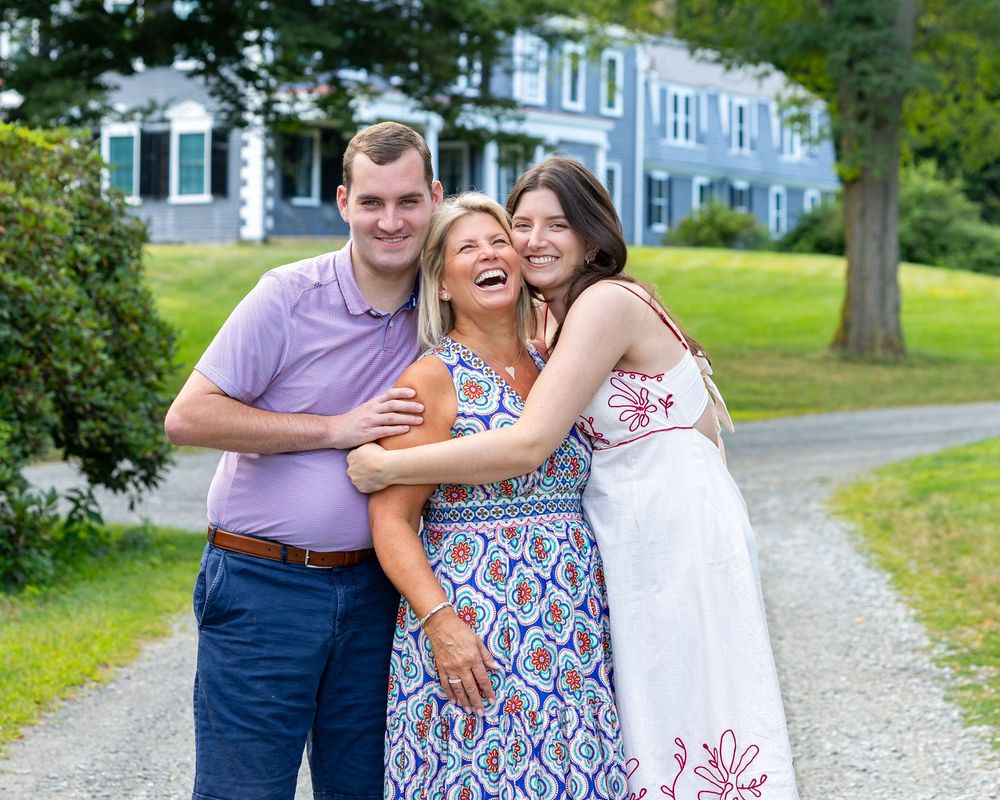 A family poses and laughs together in front of the Codman Estate in Lincoln, MA during family photography session in early fall.