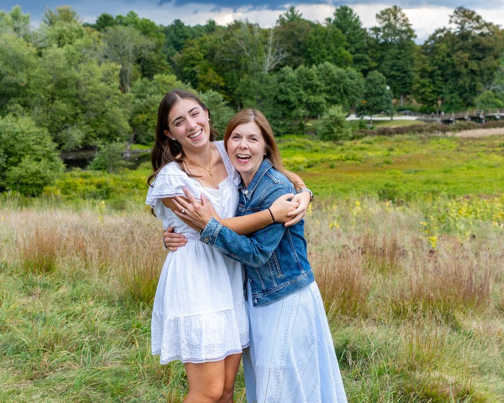 Mother & daughter share a joyful moment together while laughing in a scenic meadow at high school senior portrait session in Concord, MA.