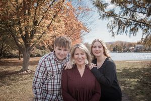 Family members share warm embraces while posing for outdoor autumn portraits among fall foliage.