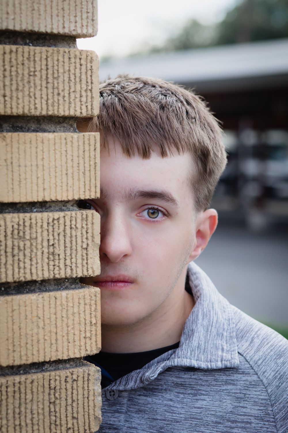 Artistic portrait showing half a face peeking from behind brick wall.