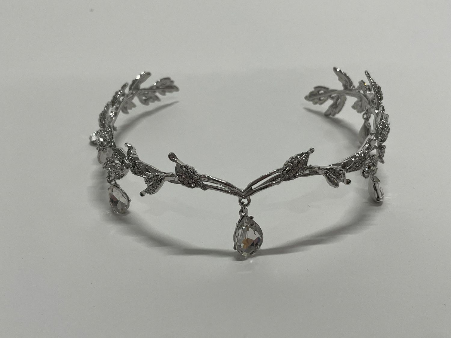 Silver crystal tiara with intricate branch and leaf motifs forming a delicate crown design.