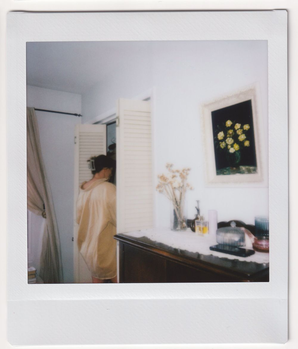 Interior room view showing a mirror, shuttered doors, and wall art with yellow flowers.