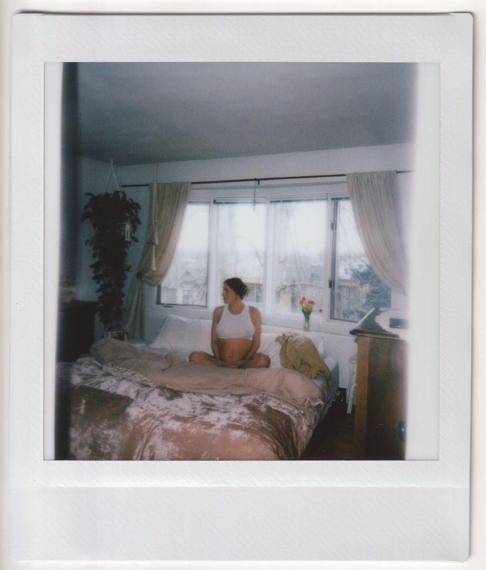 Bright bedroom with floral bedding, white curtains, and natural light streaming through windows.