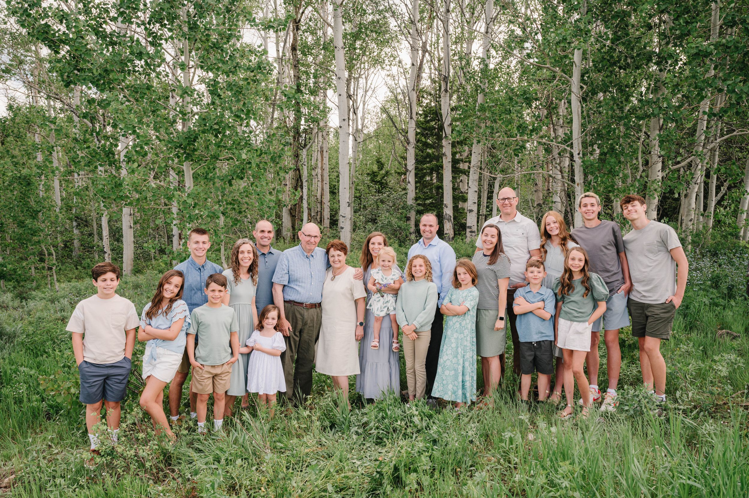 Large family group poses together in aspen grove wearing coordinated blue and white outfits.