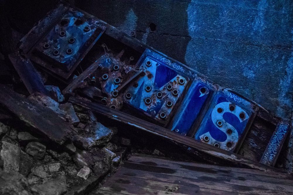 Glowing blue decorative panel lying among debris in dark setting.