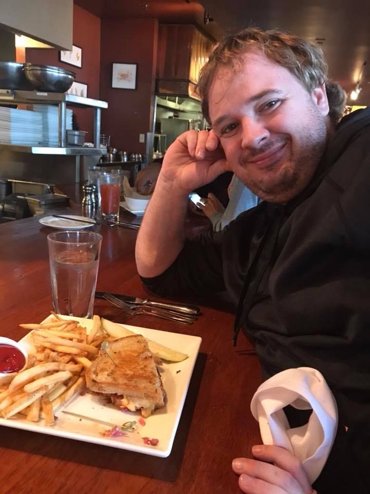 Diner enjoying a sandwich and french fries while relaxing at a restaurant bar counter.