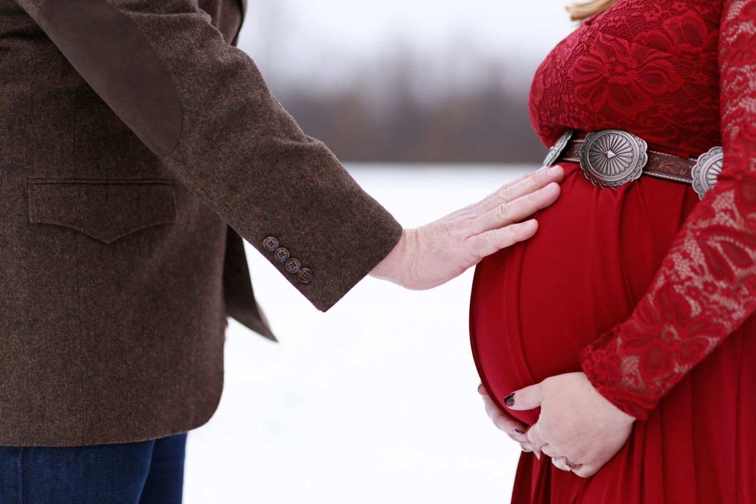 Close up photo of a soon-to-be dad rubbing the belly of his pregnant wife.