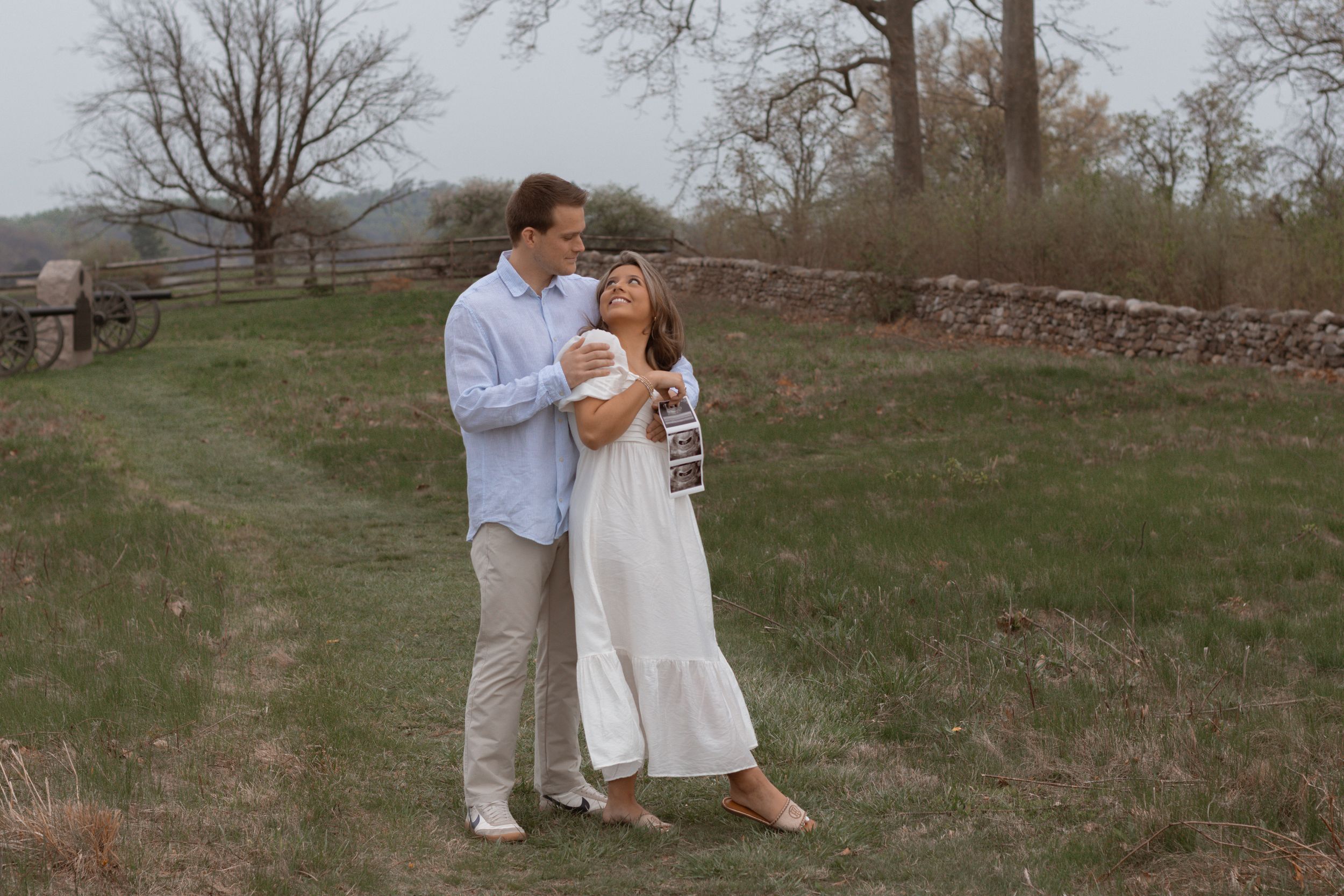 Romantic couple in white clothing sharing an intimate moment in a rural field.