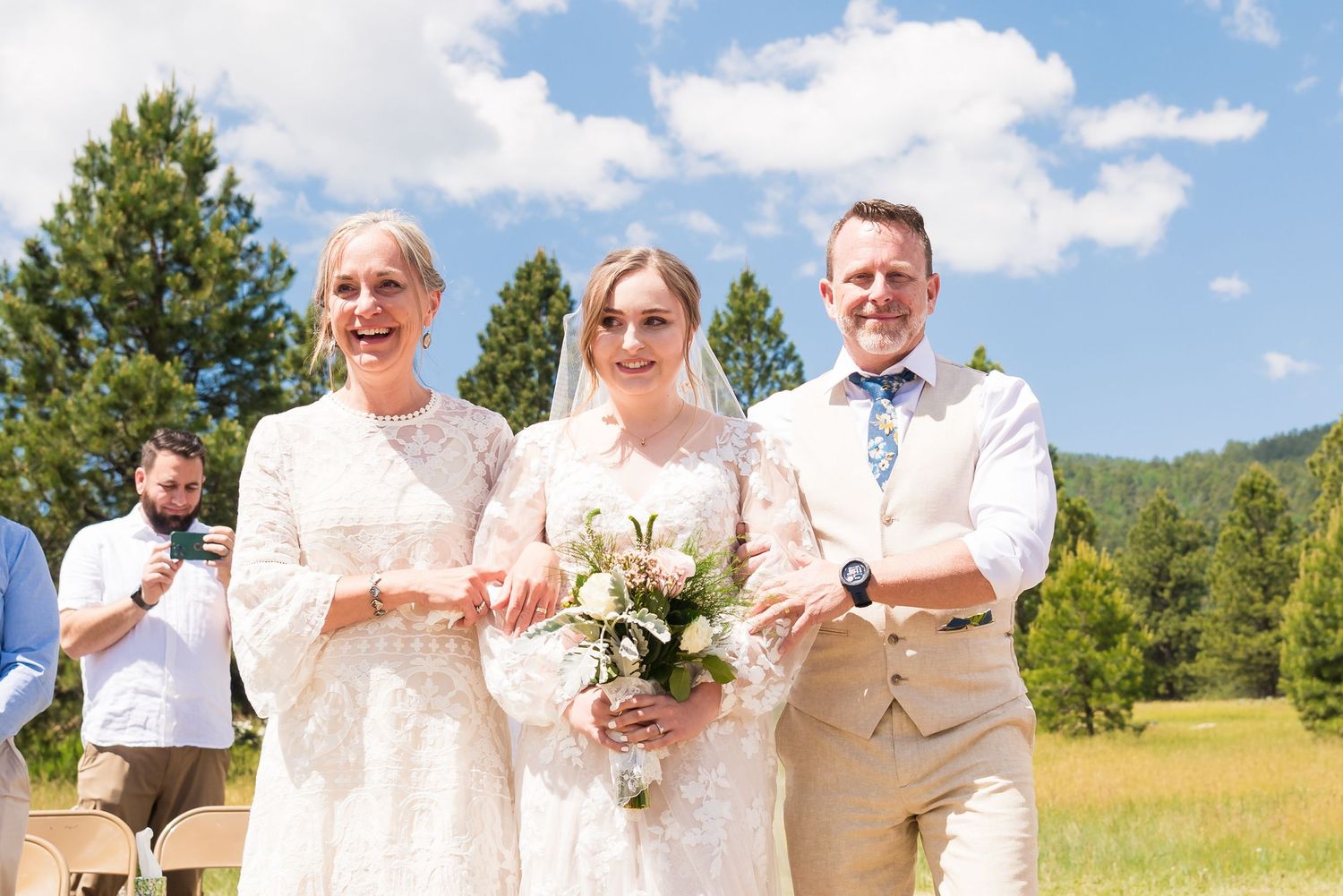 Outdoor summer wedding ceremony with mountain backdrop and blue skies.