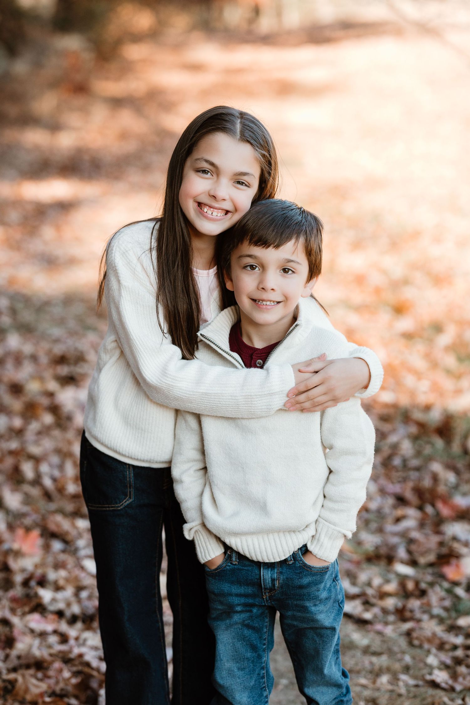 A heartwarming outdoor portrait of siblings wearing matching white sweaters in autumn.