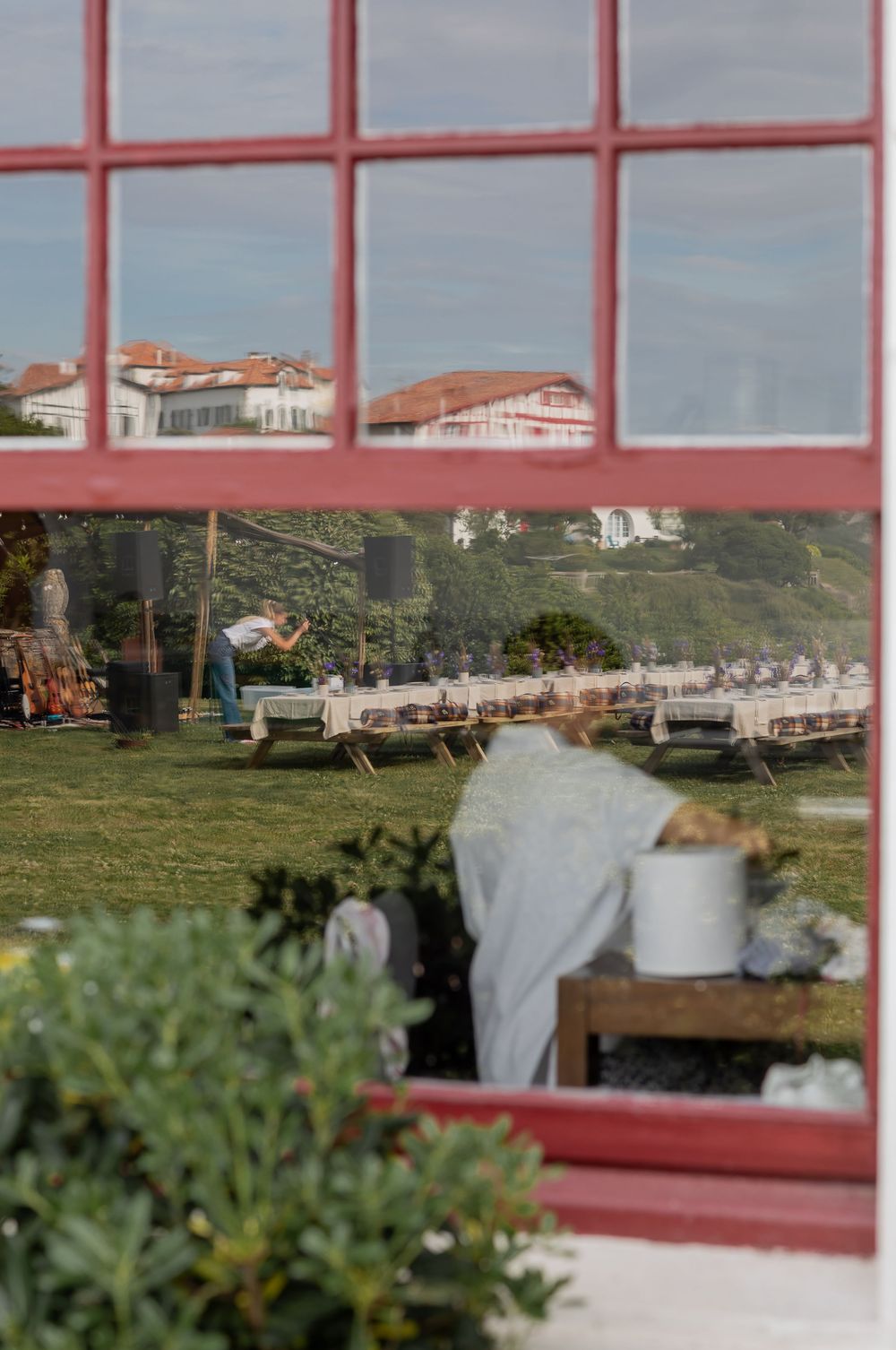 Glass-windowed building with red frames overlooking a scenic hillside and buildings in the distance.