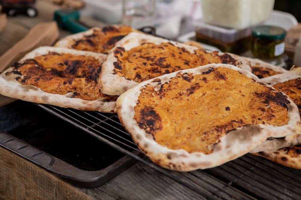 Close-up sequence showing chocolate chip cookie dough being spread and baked on a baking sheet.