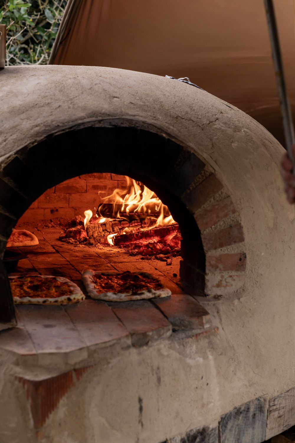 A series of brick pizza ovens with glowing wood fires inside showing different stages of flame intensity.