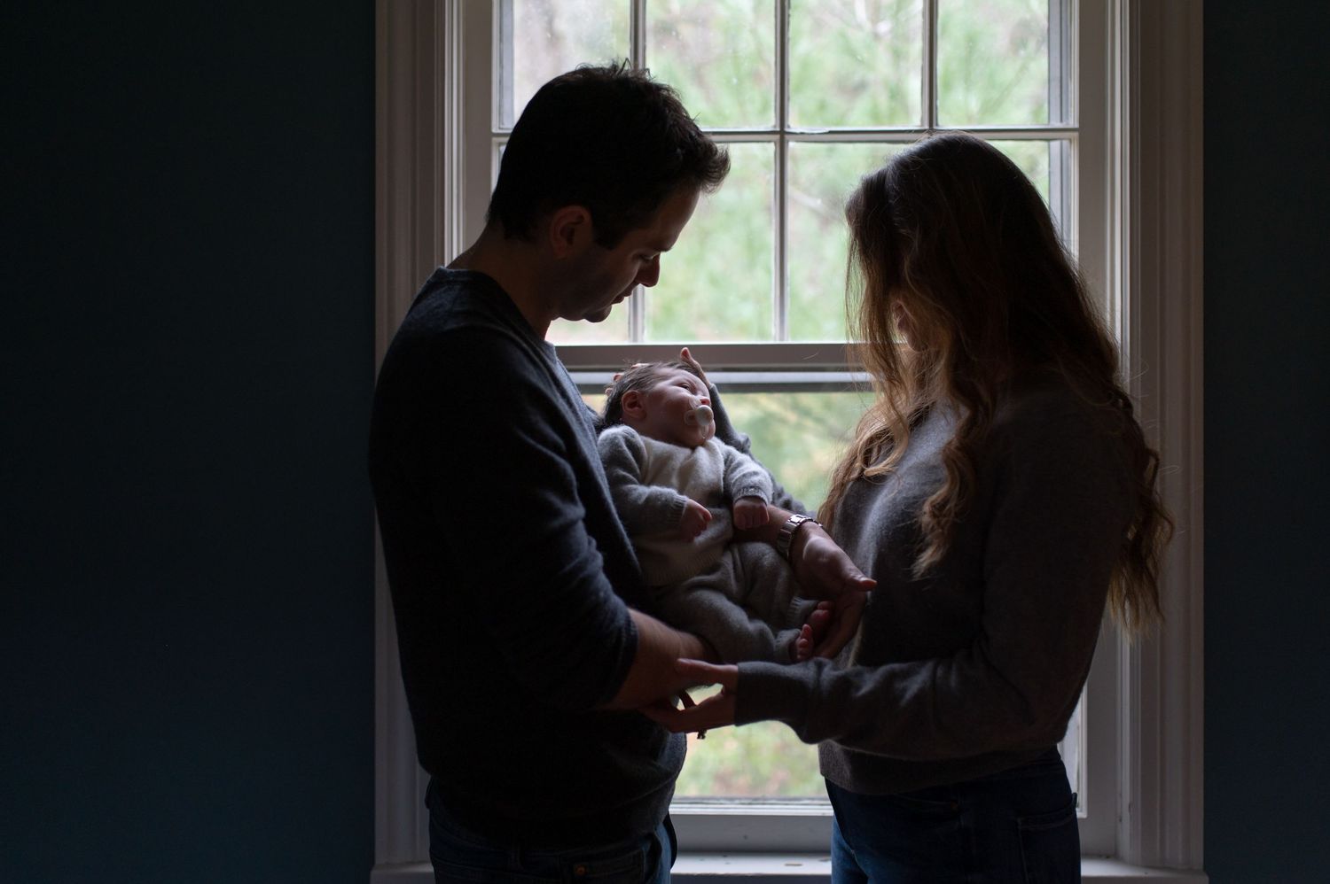 Silhouetted figures by window sharing an intimate family moment.