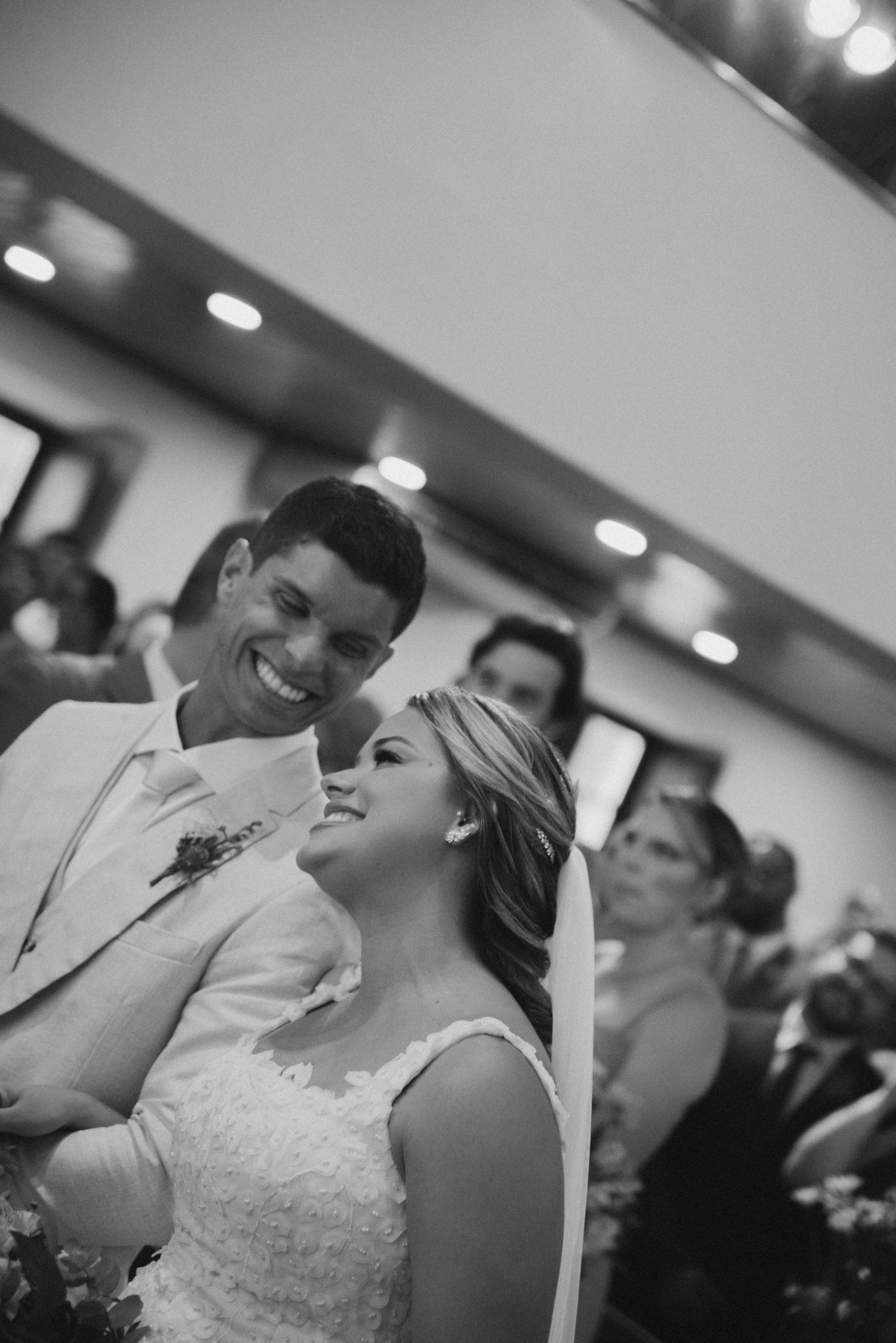 Black and white photo of a couple sharing laughter during their wedding ceremony.