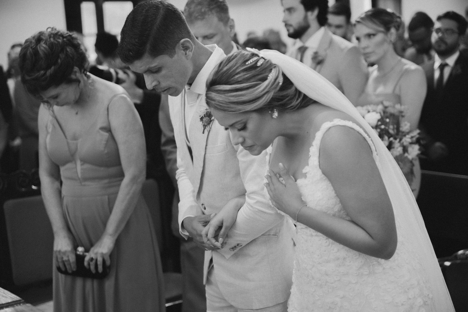 Black and white image of wedding couple bowing their heads during ceremony.