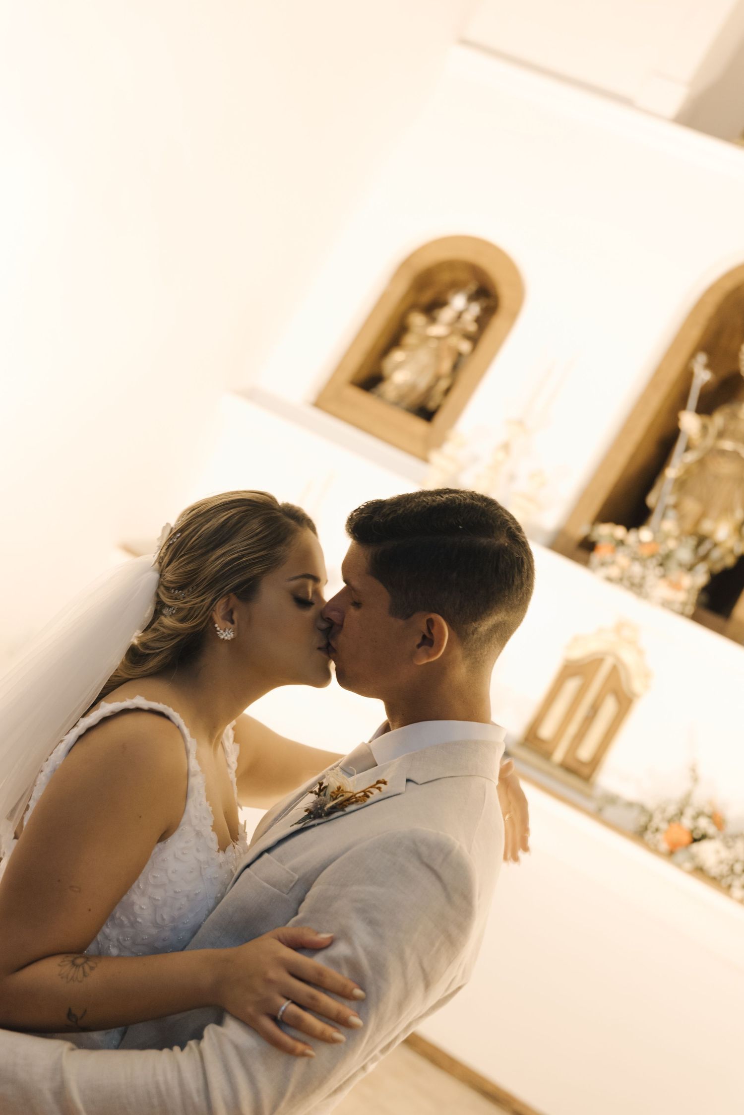 A tender moment between newlyweds in a church with religious alcoves in the background.
