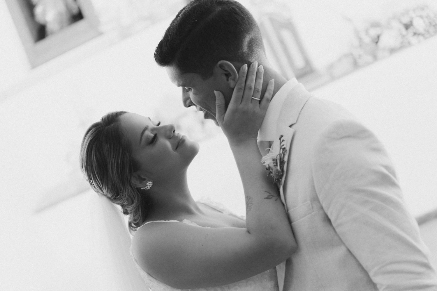 A black and white photo captures a tender moment between newlyweds as they embrace.