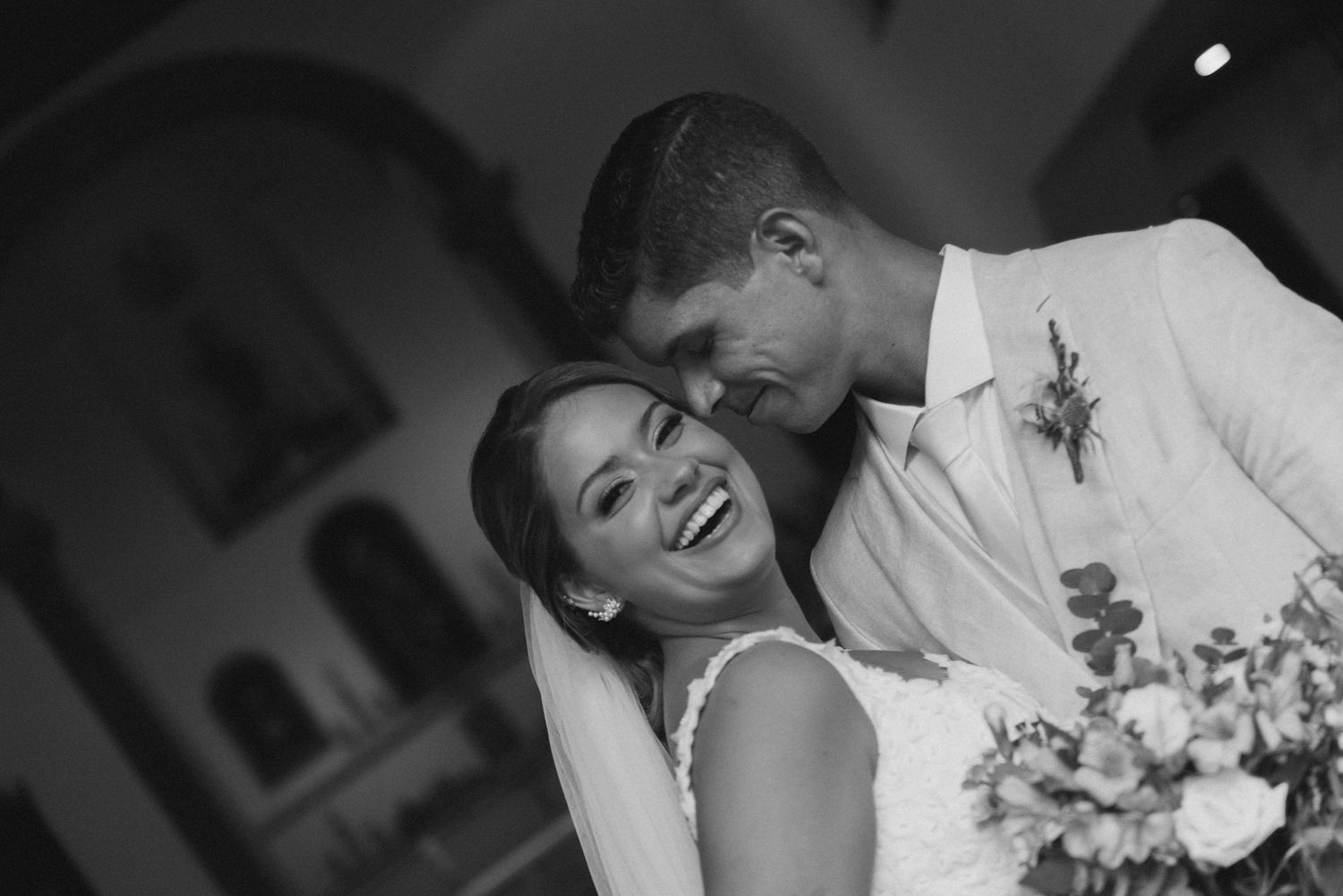 A joyful wedding moment captured in black and white as the couple shares an intimate embrace in a church setting.