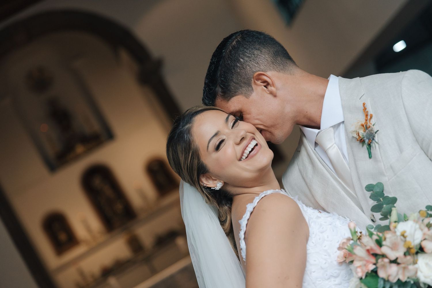 Candid wedding photo showing pure happiness and laughter between newlyweds in a church interior.