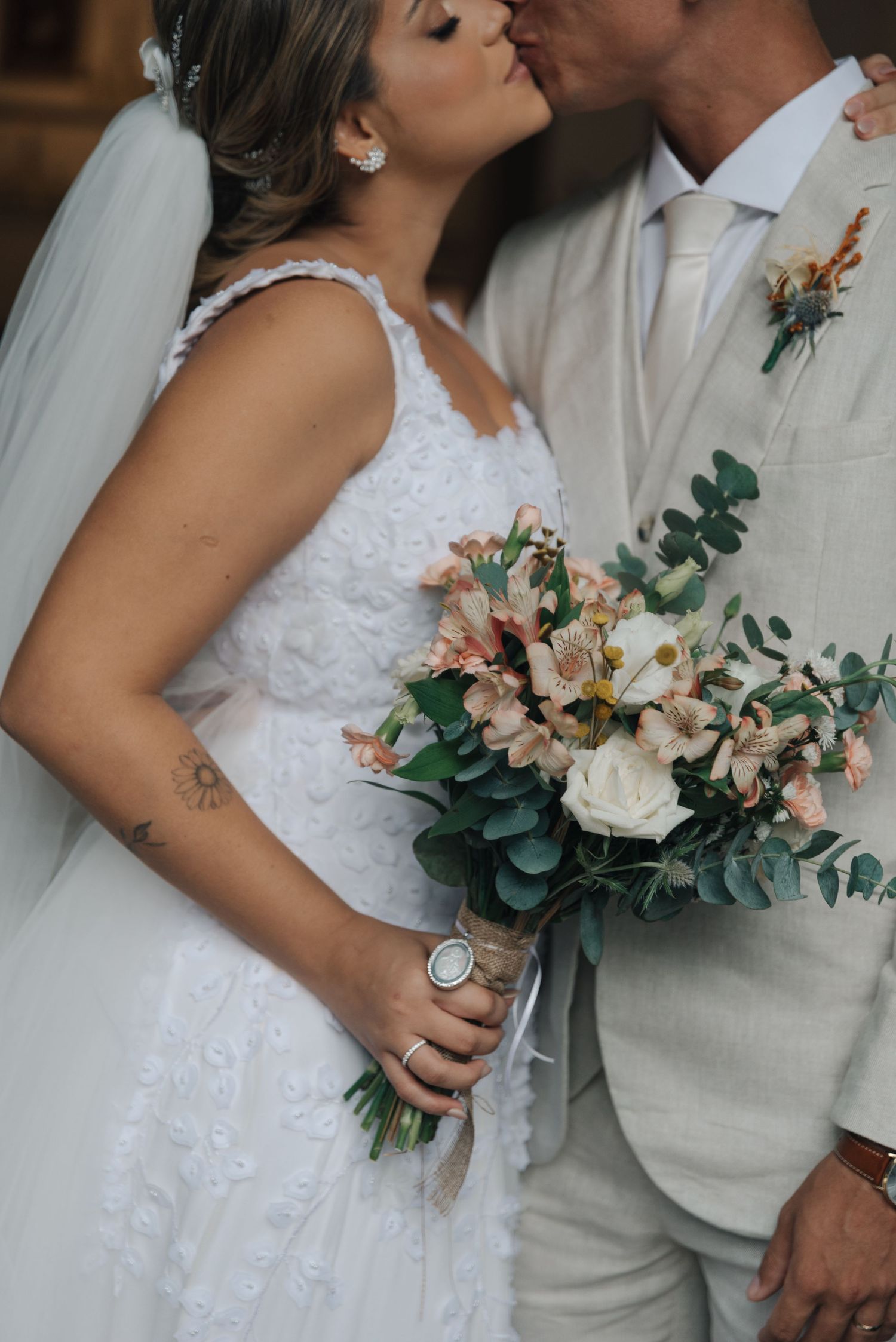Close-up of a bride holding a beautiful bouquet with eucalyptus and pink flowers while sharing an intimate moment.