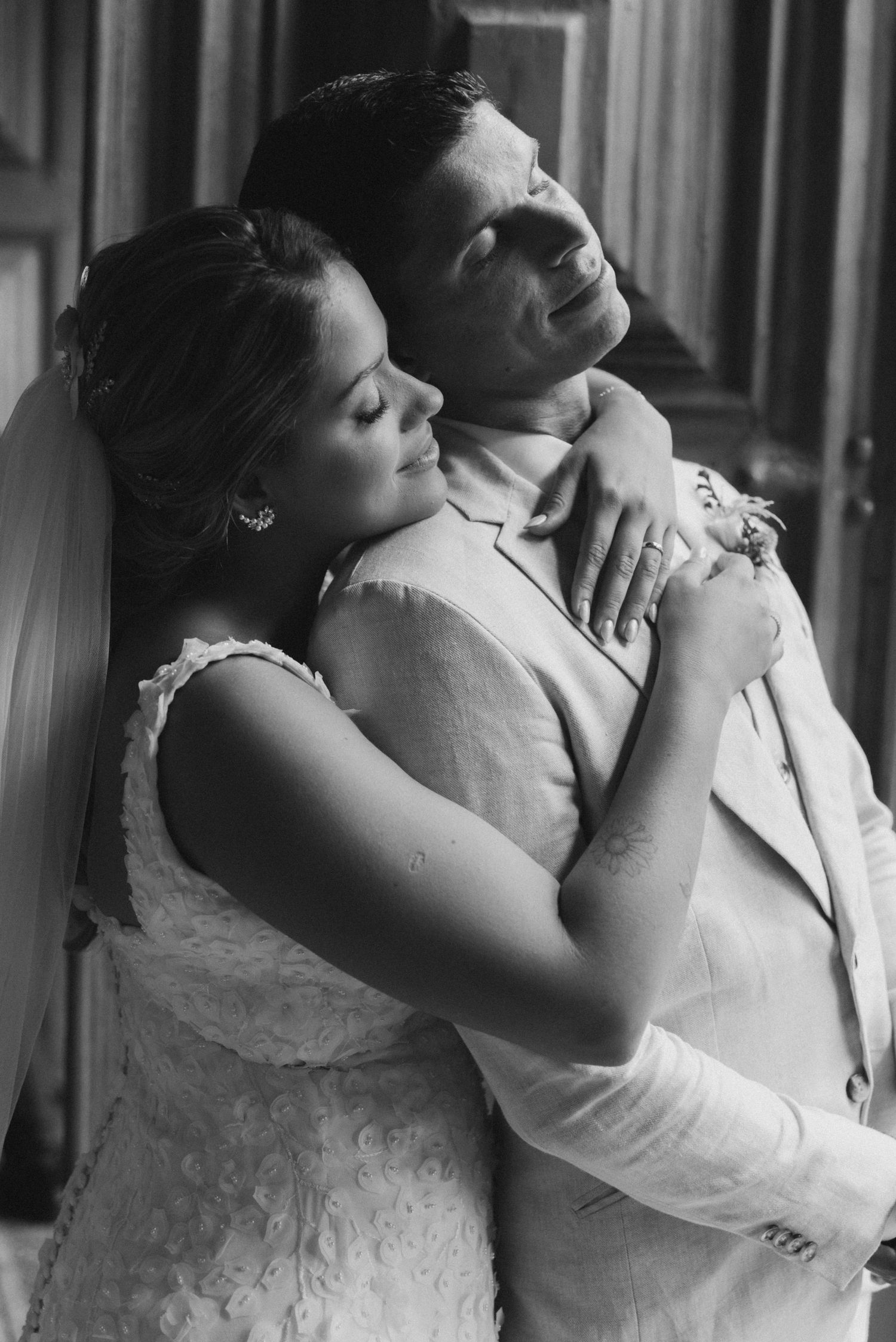 Intimate black and white portrait of newlyweds embracing in a tender moment.