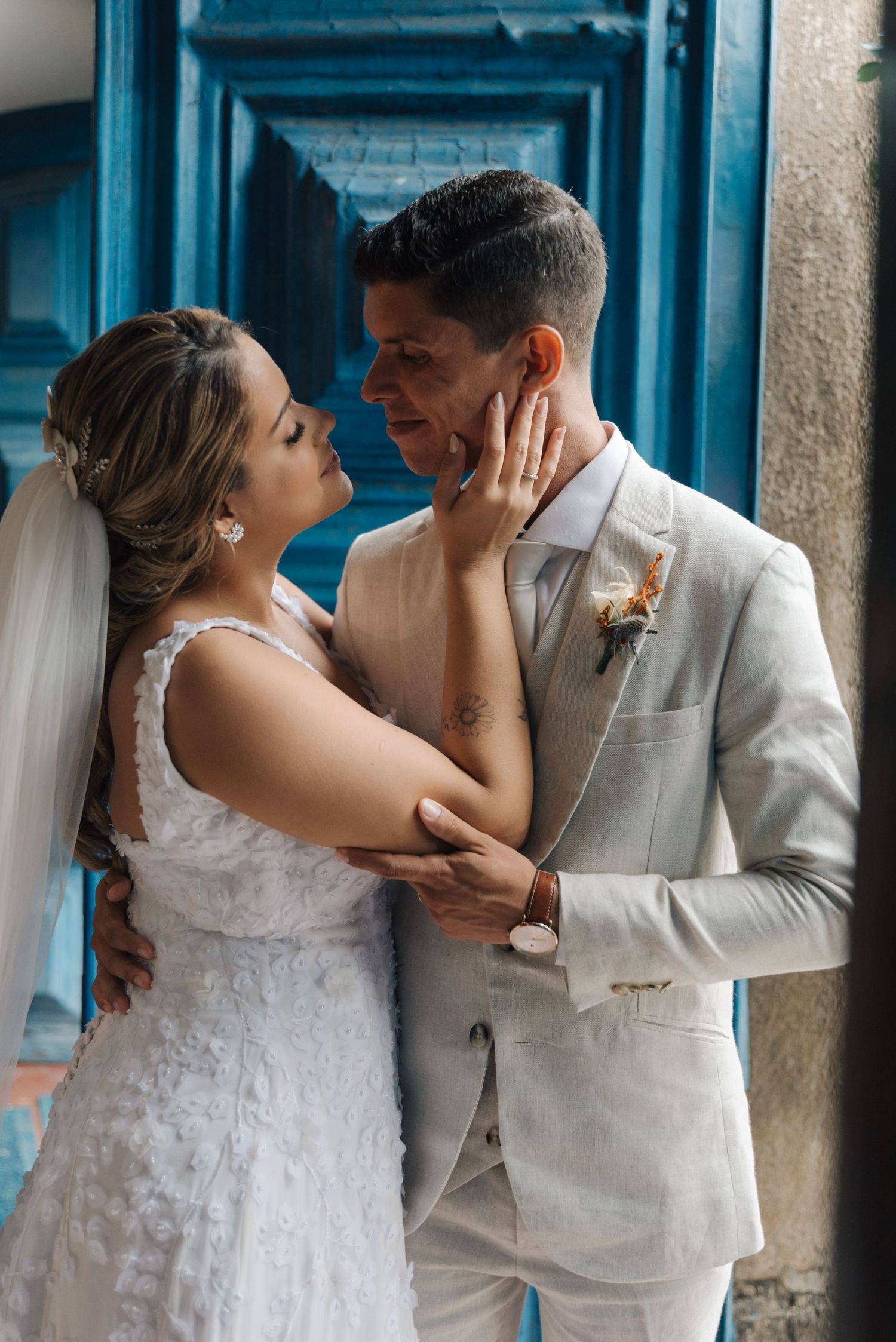 Romantic wedding portrait against a blue door showing an intimate moment between newlyweds.